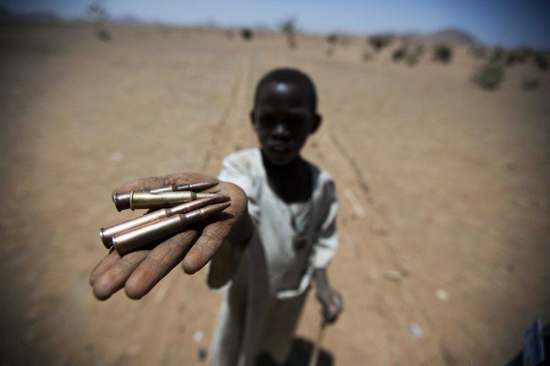 A young boy holds spent bullet casings
