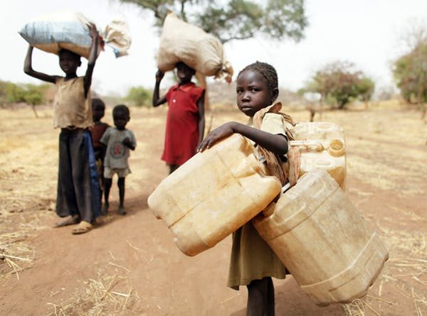 A child carries water containers on a long walk home