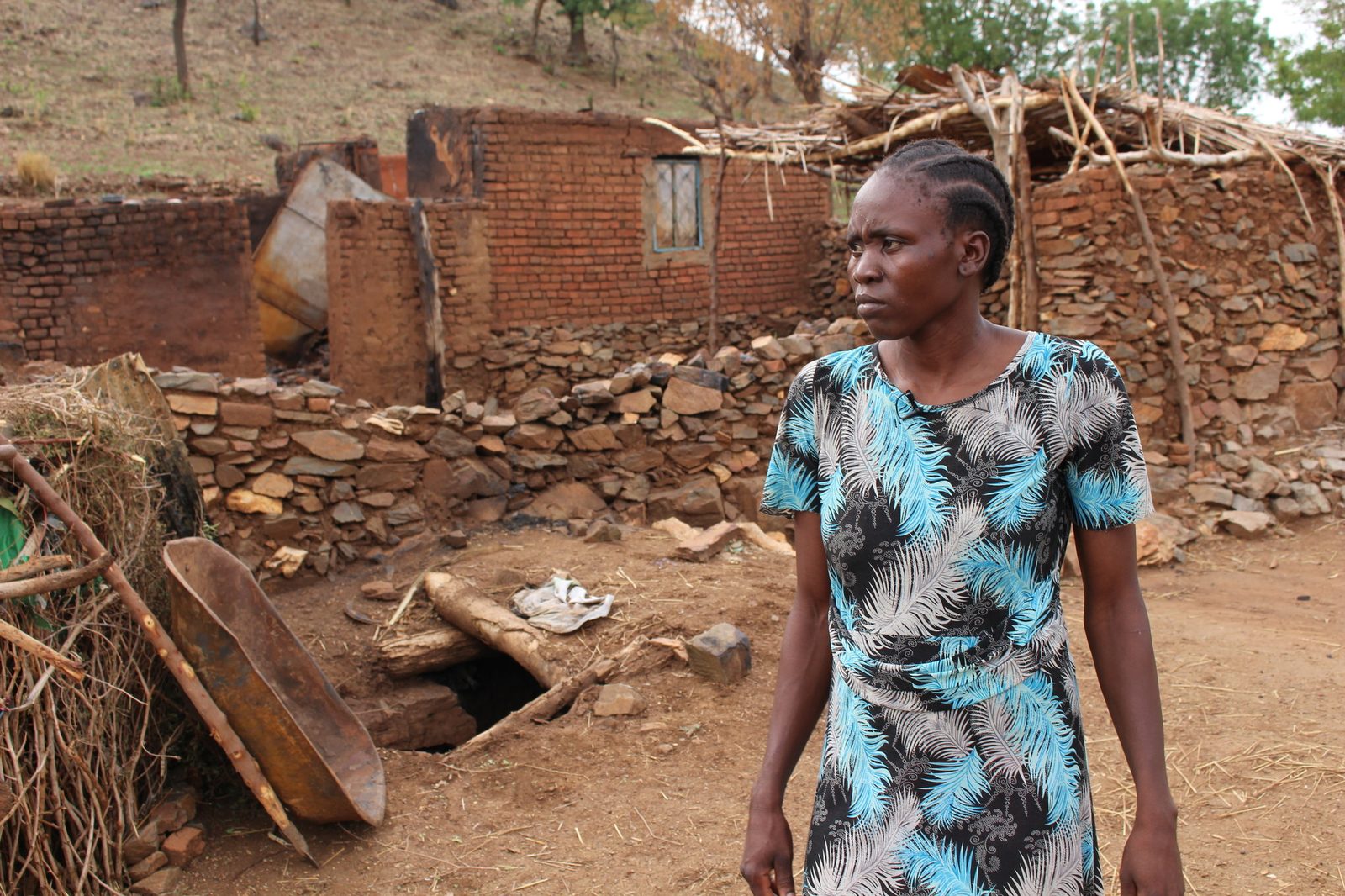 A woman stands beside her burned and destroyed home