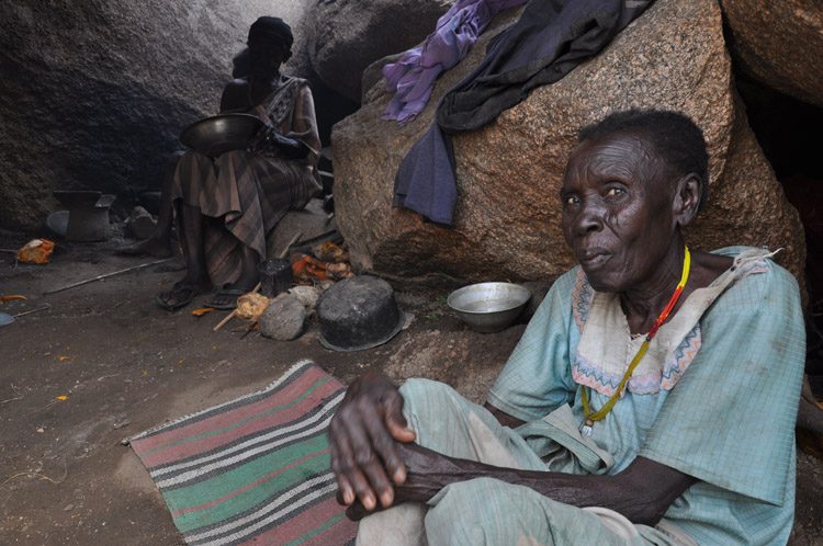 An elderly woman sits in a cave shelter