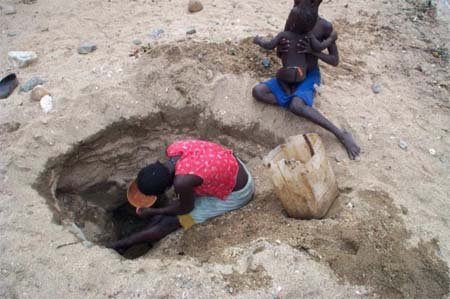 Children dig in sand to reach water
