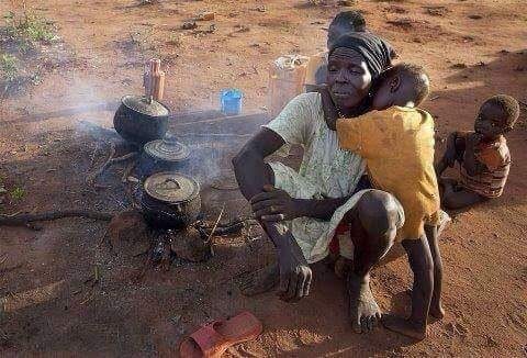 A mother cooks over an open fire with her children