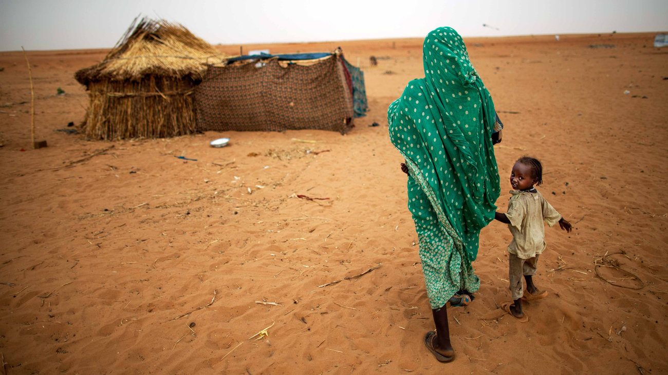 A mother and child walk through a displacement settlement